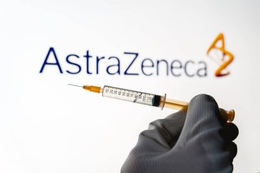 Kyiv, Ukrayna 18 Nisan 2021: Tıbbi şırınganın tamamı bulanık arkaplanda AstraZeneca şirketinin logosu ile görüntülendi