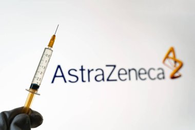 Kyiv, Ukrayna 18 Nisan 2021: AstraZeneca SARS Covid-19 aşı konsepti. Şırınganın yakın çekimi ve arka planda AstraZeneca şirketinin logosu bulanıklaştı.