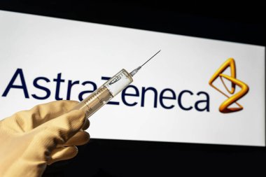 Kyiv, Ukrayna 18 Nisan 2021: AstraZeneca SARS Covid-19 aşı konsepti. Şırınganın yakın çekimi ve arka planda AstraZeneca şirketinin logosu bulanıklaştı.