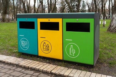 Çöp konteynırları ayıklama. Cam, plastik ve kağıt için ayrı çöp kutuları. Atık ayıklama, parktaki sembollü üç renkli çöp kutusu.
