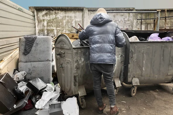guy looking for food in garbage containers on the street. increase in unemployment due to quarantine and the COVID 19 pandemic