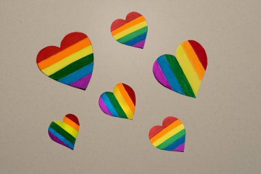 Bej arka planda birkaç kağıt LGBT renkli kalp var. Lezbiyen, eşcinsel, biseksüel, transseksüel ve eşcinsel insanlar için LGBTQ gökkuşağı kalp konsepti