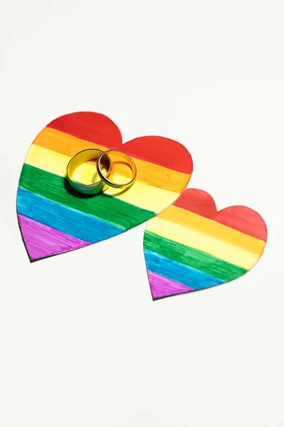 紙の上に2つの黄金のリングLgbtのフラグのような色のハートを切った レズビアン バイセクシャル トランスジェンダー クィアの人々の結婚と組合のためのハートコンセプト — ストック写真