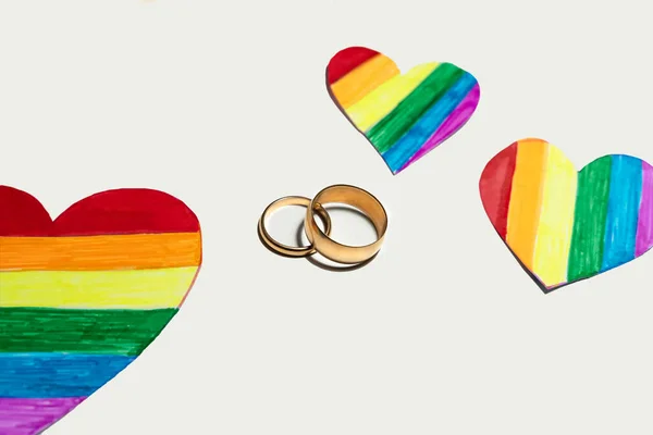 Lgbtの旗のような色の切り絵の心の間に2つの黄金のリング レズビアン バイセクシャル トランスジェンダー クィアの人々の結婚と組合のためのハートコンセプト — ストック写真
