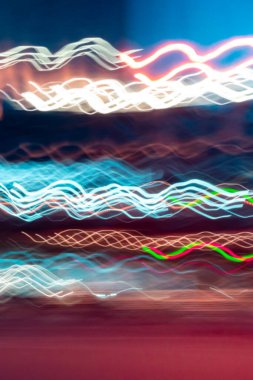 Bright swirly lines on dark background. the light trails on the street. blue and gold wavy light lines - blurred abstract background, vertical image