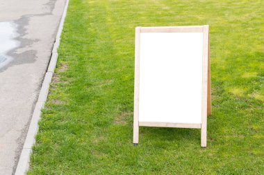 Mock up of wooden advertising stand with empty white space for text on green grass background
