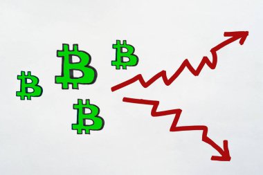Yeşil Bitcoin tabelaları ve beyaz kağıda el yazısıyla çizilmiş iki okun fotoğrafı. Bitcoin 'in gelecek konseptte yükselişi ve düşüşü