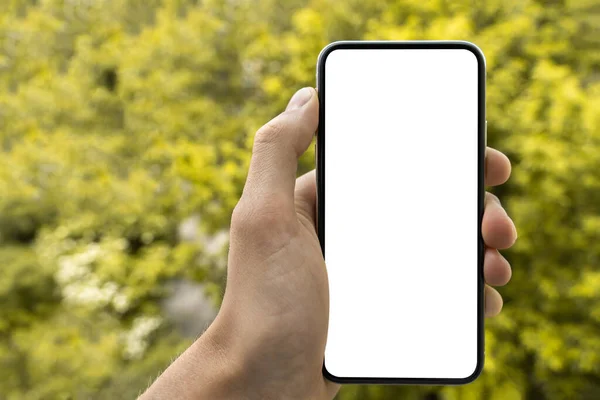 男の手を握って白い画面でスマートフォンを見せてるモックアップの画像 現代の携帯電話は空白の画面で — ストック写真