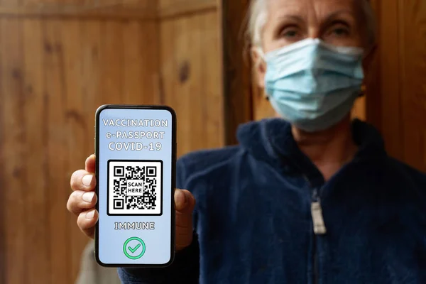 Μεσήλικη Γυναίκα Μάσκα Κατέχει Ένα Smartphone Ηλεκτρονικό Διεθνές Πιστοποιητικό Εμβολιασμού Royalty Free Φωτογραφίες Αρχείου