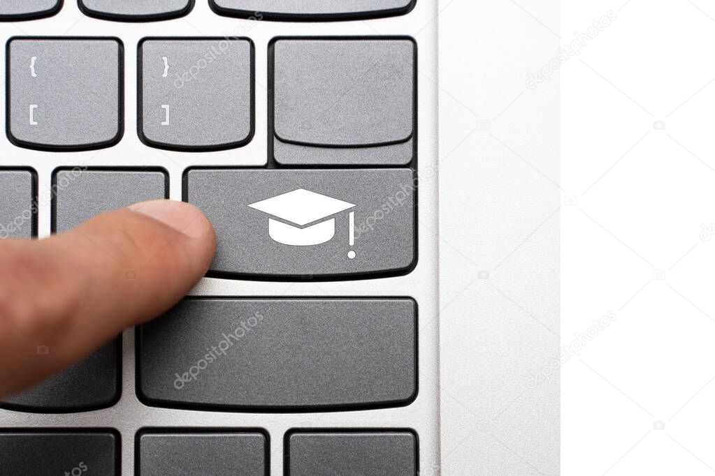 finger reaches for the button with the master's Graduation Cap on the keyboard. obtaining higher education and scientific degrees online