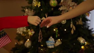 Bir çocuk annesinin ağacına bir Noel ağacı oyuncağı fırlatır. Yüzler yok. Yüksek kaliteli FullHD görüntüler