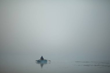 Kalın sisin içinde nehirde bir tekne..