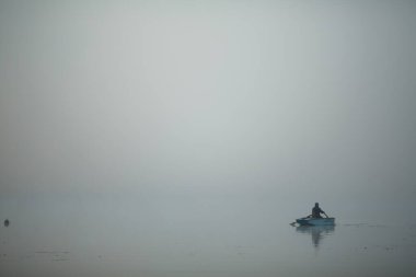 Kalın sisin içinde nehirde bir tekne..