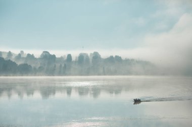 Kalın sisin içinde nehirde bir tekne..