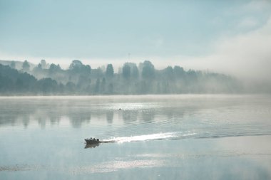 Kalın sisin içinde nehirde bir tekne..