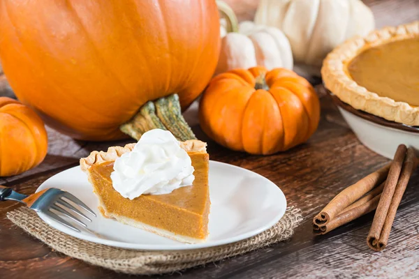 Fetta di una torta di zucca e zucche sullo sfondo — Foto Stock