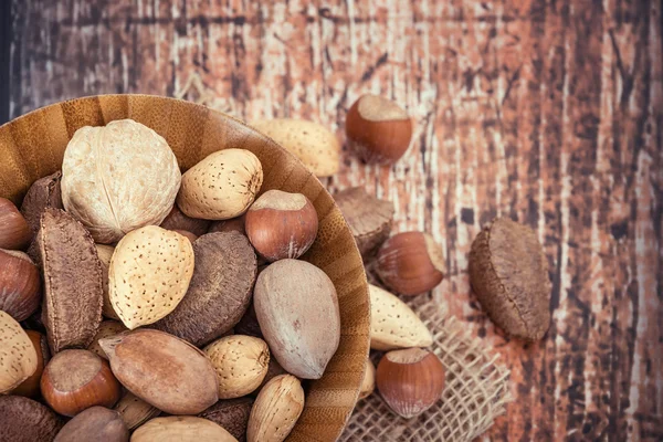 Mix nuts in a wooden bowl against rustic background — Stock Photo, Image