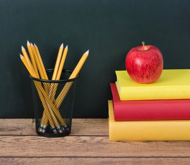 Masanın üzerinde apple ve kalem ile okul kitap yığını