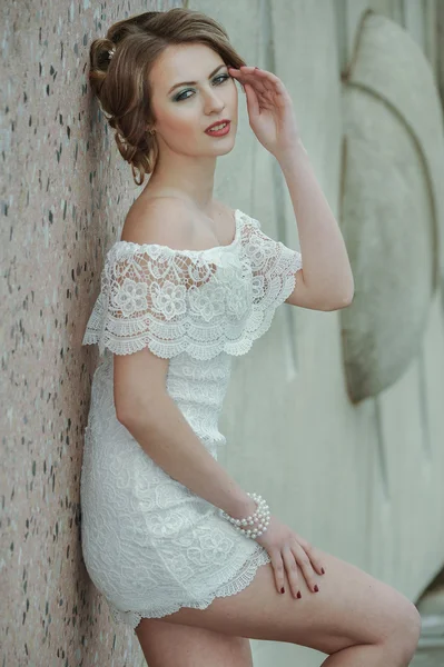 Hermosa chica elegante posando en vestido blanco corto contra la pared de piedra —  Fotos de Stock