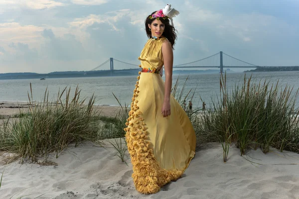 Beautiful fashion model in luxury dress posing on the beach — Stockfoto