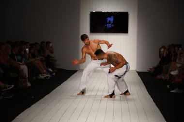 Dansçılar podyumda capoeira gerçekleştirir