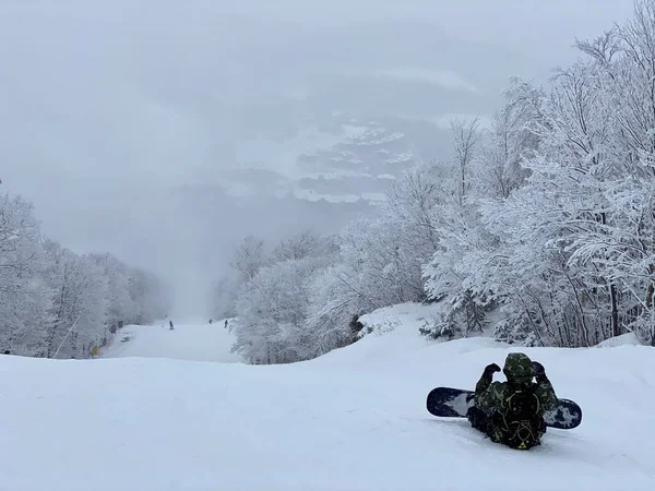 ストウ山スキー場の美しいパノラマの谷を見下ろす歩道に座っているスノーボーダー — ストック写真