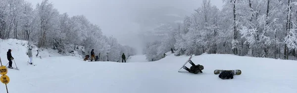 ストウ山スキー場の美しいパノラマの谷を見下ろす歩道に座っているスノーボーダーのパノラマ写真 — ストック写真