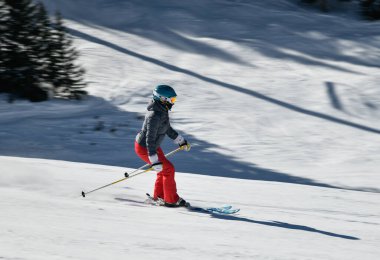 Kadın kayakçı, güneşli bir günde yüksek hızda yamaçlardan aşağı iniyor. Colorado, Vail Kayak Tesisi 'nde yeni bir gösteriyle.