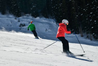 Kadın kayakçı, güneşli bir günde yüksek hızda yamaçlardan aşağı iniyor. Colorado, Vail Kayak Tesisi 'nde yeni bir gösteriyle.
