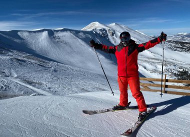 Kırmızı elbiseli adam Breckenridge Kayak Tesisi, Colorado 'da İmparatorluk Bowl sahasının kenarında duruyor..