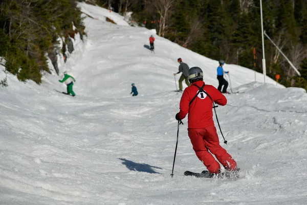 四月中旬温暖的晴天 在佛蒙特州的斯托山度假胜地 身穿红色西服的斯托度假村工作人员和一组滑雪者从后面转过来 — 图库照片