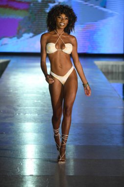 MIAMI BEACH, FLORIDA - 09 Temmuz 2021 'de Miami Beach, Florida' da DCSW tarafından desteklenen Miami Yüzme Haftası boyunca bir model neredeyse çıplak yüzme şovu için podyumda yürüyor.