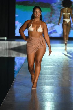 MIAMI BEACH, FLORIDA - 09 Temmuz 2021 'de Miami Beach, Florida' da DCSW tarafından desteklenen Miami Yüzme Haftası boyunca bir model neredeyse çıplak yüzme şovu için podyumda yürüyor.