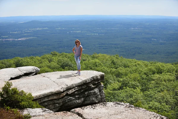 Młoda kobieta pozowanie na skraju skały — Zdjęcie stockowe