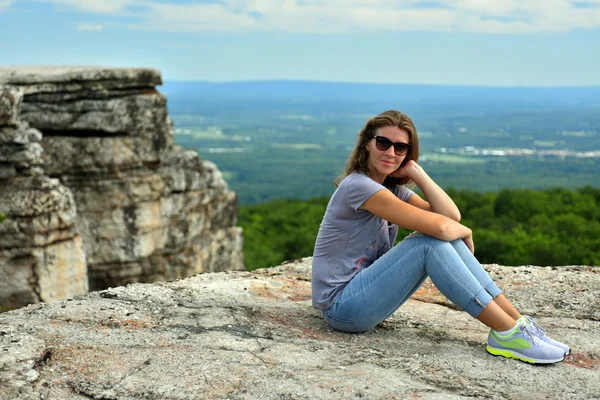 Женщина, сидящая на краю скалы — стоковое фото