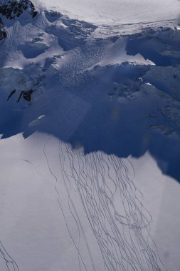 Temiz beyaz kar yüzeyi, birden fazla doğal kayak izi akış, organik çizgiler oluşturuyor. Kayak, açık hava sporları, dağ tatil beldeleri, soğuk hava ve kış dokuları ile ilgili konular için minimal kış geçmişi ideali.