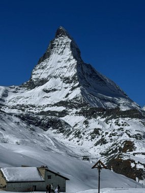 Karla kaplı madde boynuzu İsviçre 'de açık bir kış gününde bir dağ evinin tepesinde parlak mavi dağ ışığında kıtır kıtır bir ayrıntıyla yakalandı..