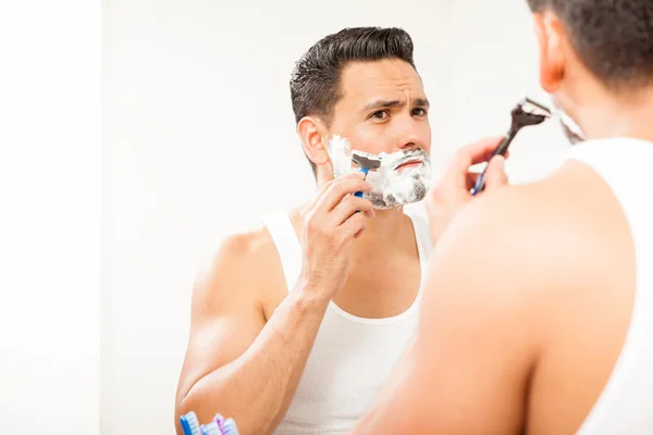 Hombre hispano usando una navaja de afeitar —  Fotos de Stock