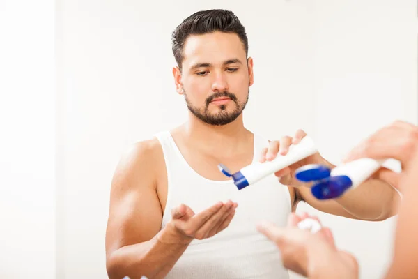 Uomo con la barba versando della crema — Foto Stock