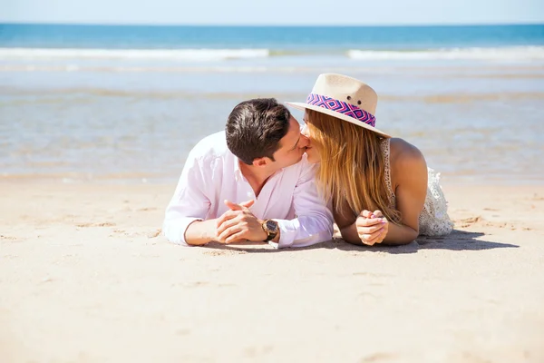 Pareja joven acostada en la arena — Foto de Stock