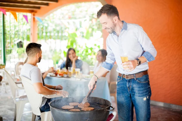 Jeune mâle cuisine quelques hamburgers — Photo