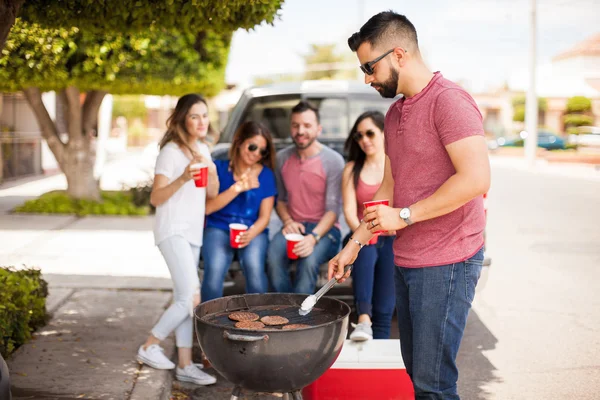 Młody mężczyzna z brodą grillu niektóre hamburgery — Zdjęcie stockowe