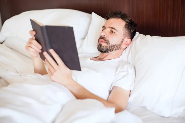 Mann liest ein Buch im Bett — Stockfoto