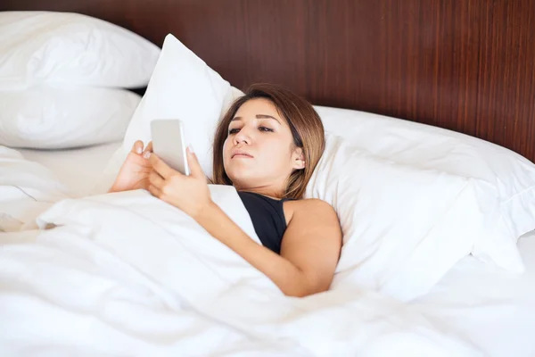 Frau mit Smartphone im Bett — Stockfoto