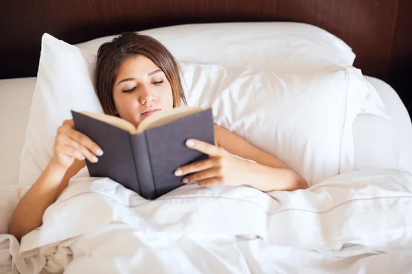 Mulher lendo um livro em sua cama — Fotografia de Stock