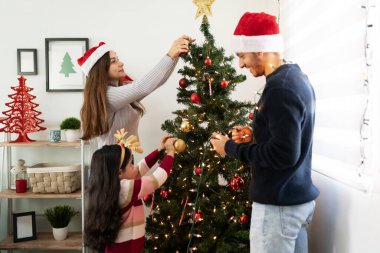 Üç kişilik İspanyol bir aile Noel süsleri takıyor ve birlikte güzel vakit geçiriyorlar.
