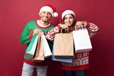 Stüdyoda bir sürü alışveriş çantası ve Noel hediyesi taşıyan neşeli bir çift.