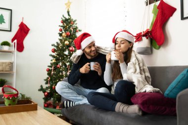 Mutlu Latin çift rahatlıyor ve Noel 'i birlikte geçiriyor sıcak çikolata içiyor ve evde ısınıyor.