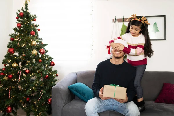 かなり小さなヒスパニック系の女の子カバー彼女の父親の目と同時に彼に驚きクリスマスプレゼントに家 — ストック写真