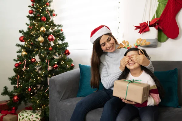 彼女の娘の目をカバーしながら 彼女に驚きを与えますクリスマスプレゼントに家と笑顔 — ストック写真